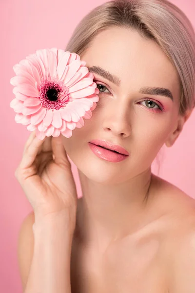 Tenera donna nuda con trucco rosa con fiore gerbera, isolato su rosa — Foto stock