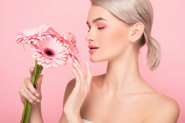 Attractive tender girl looking at pink flowers, isolated on pink — Stock Photo