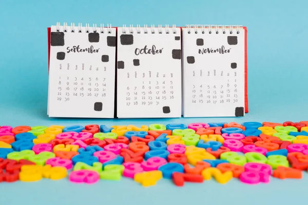 Kalender und bunte Plastikzahlen auf blauem Hintergrund — Stockfoto