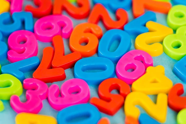 Concentration sélective des numéros de plastique colorés sur la surface bleue — Photo de stock