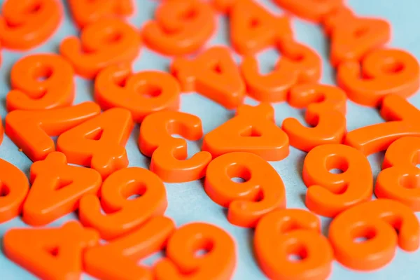 Selektiver Fokus orangefarbener Kunststoffzahlen auf blauem Hintergrund — Stockfoto