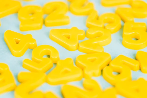 Enfoque selectivo de números de plástico amarillo sobre fondo azul - foto de stock