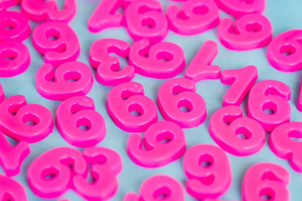 Vista de ángulo alto de los números de plástico rosa en la superficie azul - foto de stock