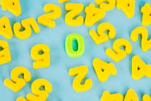 Vista de ángulo alto de cero verde y números de plástico amarillo en la superficie azul - foto de stock