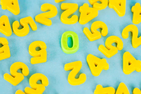 High angle view of green zero and yellow plastic numbers on blue surface — Stock Photo