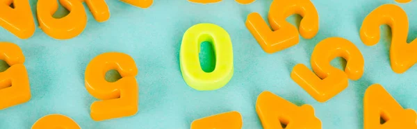 Tiro panorâmico de números de plástico amarelo zero e laranja no fundo azul — Fotografia de Stock