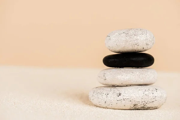 Vista de cerca de piedras zen apiladas en arena aislada en beige - foto de stock