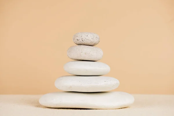 Close up view of stacked zen stones on sand isolated on beige — Stock Photo