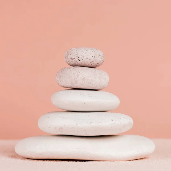 Close up view of stacked zen stones on sand isolated on peach — Stock Photo