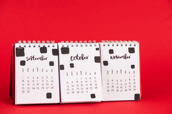 Паперовий календар з осінніми місяцями на червоному тлі — стокове фото