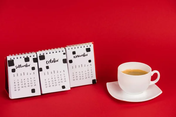 Calendrier avec mois d'automne et tasse de café sur fond rouge — Photo de stock