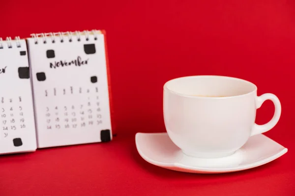 Selektiver Fokus von Kaffeetasse und Kalender auf rotem Hintergrund — Stockfoto
