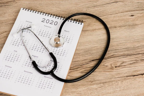 Stéthoscope et calendrier de l'année 2020 sur fond bois — Photo de stock