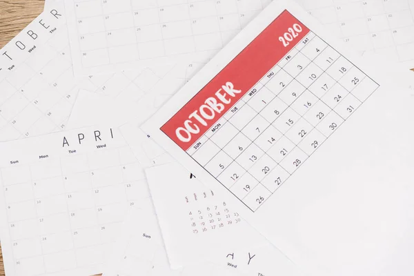 Vista superior de los calendarios mensuales de papel sobre fondo de madera - foto de stock