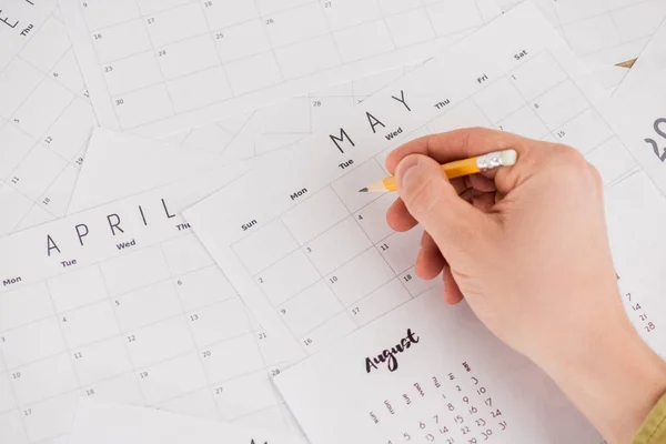 Vista cortada do homem segurando lápis acima de calendários mensais — Fotografia de Stock