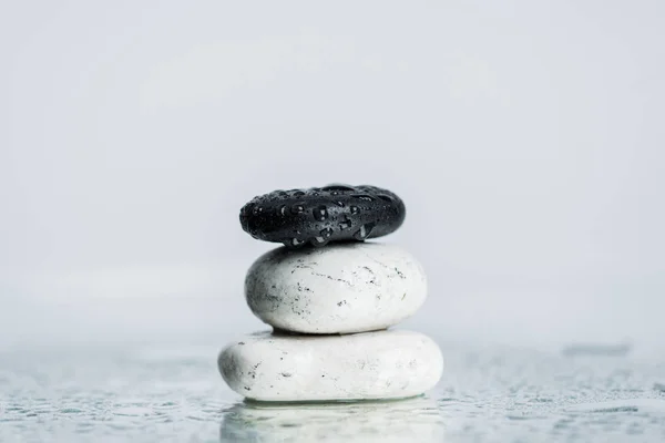 Piedras zen húmedas sobre vidrio con gotas de agua aisladas sobre gris - foto de stock