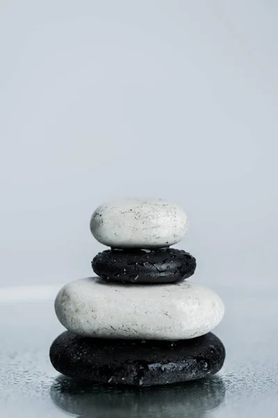 Piedras zen blancas y negras sobre vidrio húmedo aislado sobre gris - foto de stock