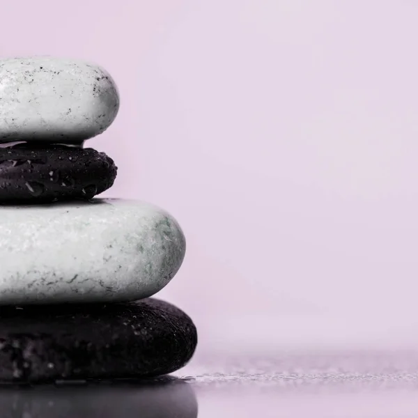 Vue rapprochée des pierres zen humides sur verre avec gouttes d'eau isolées sur violet — Photo de stock
