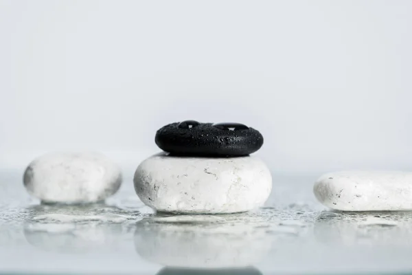 Rücken und weiße Zen-Steine mit Wassertropfen auf nassem Glas auf grauem Hintergrund — Stockfoto