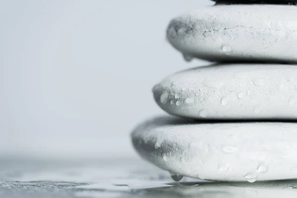 Macro shot of white zen stones in water drops on wet glass isolated on grey — Stock Photo