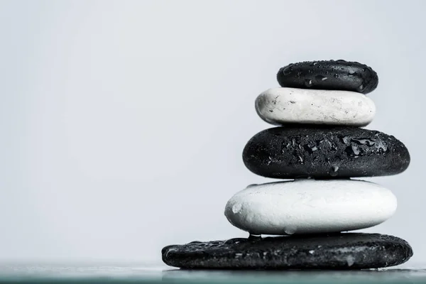 Nahaufnahme von Wassertropfen auf gestapelten schwarzen und weißen Zen-Steinen auf nassem Glas isoliert auf grau — Stockfoto