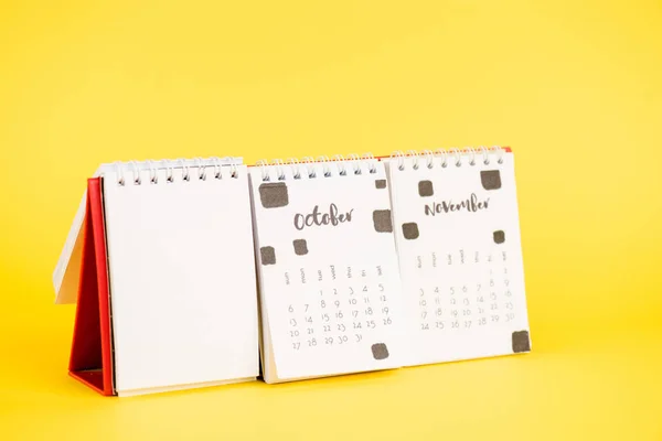 Calendario de papel con vacío en blanco, octubre y ahora meses sobre fondo amarillo - foto de stock