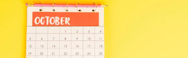 Vue du dessus du crayon et du calendrier avec mois d'octobre sur fond jaune, vue panoramique — Photo de stock