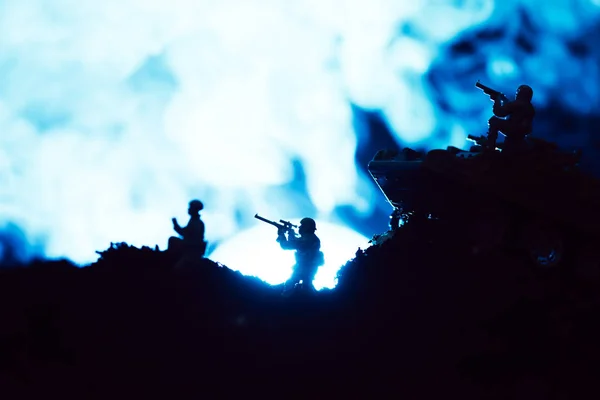 Escena de batalla con soldados de juguete y humo con luna sobre fondo negro - foto de stock
