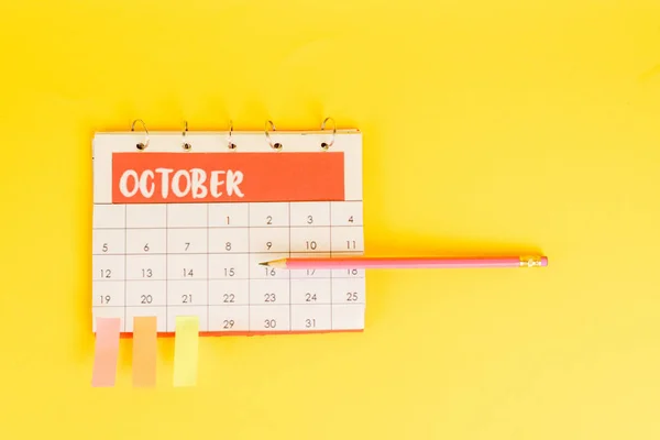 Vista superior do lápis no calendário com mês de novembro e notas pegajosas nas datas no fundo amarelo — Fotografia de Stock