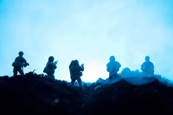 Soldados de juguete con arma y humo sobre fondo azul, escena de batalla - foto de stock
