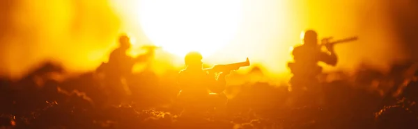 Battle scene of toy soldiers with sun on orange background, panoramic shot — Stock Photo