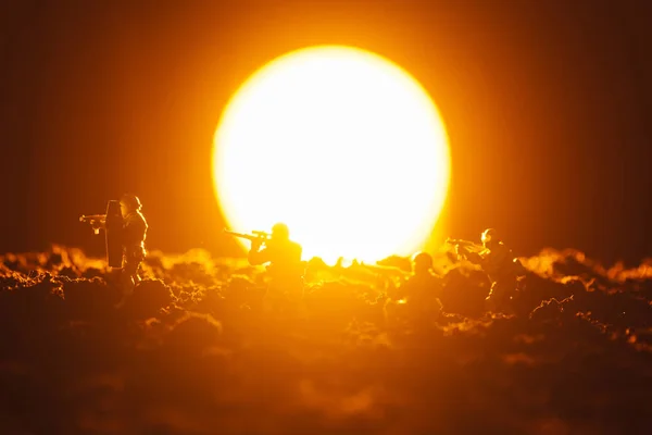 Escena de batalla de soldados de juguete con arma y puesta de sol en el fondo - foto de stock