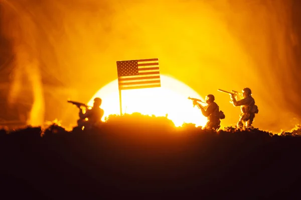 Escena de batalla con guerreros de juguete cerca de bandera americana en humo con puesta de sol en el fondo - foto de stock