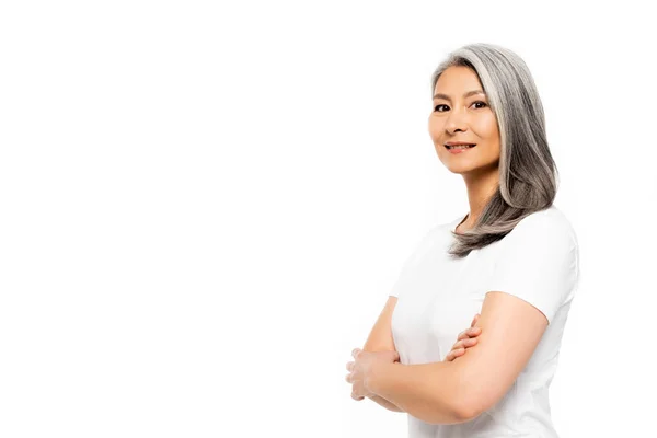 Happy asian woman looking at camera and standing with crossed arms isolated on white — Stock Photo