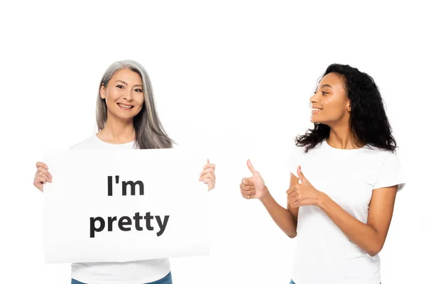 Happy african american woman showing thumb up near i 'm pretty placard isolated on white — стоковое фото