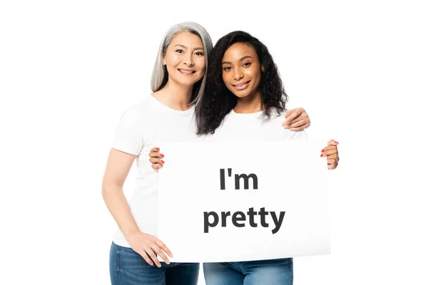 Sorridente africano americano e asiático mulheres segurando eu sou muito cartaz isolado no branco — Fotografia de Stock
