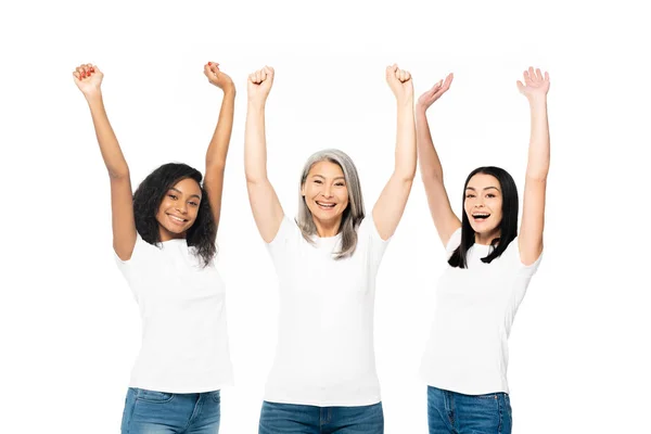 Cheerful multicultural women with hands above head celebrating isolated on white — Stock Photo