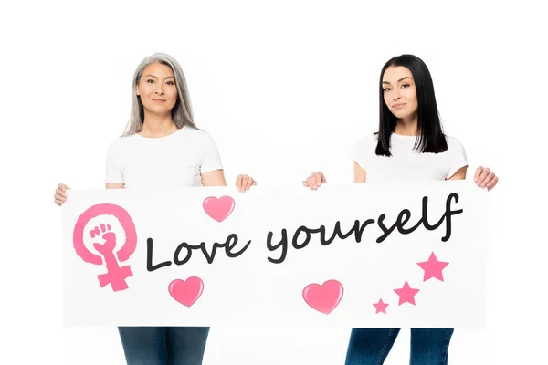 Mujeres multiculturales sosteniendo cartel con el amor mismo letras aisladas en blanco - foto de stock