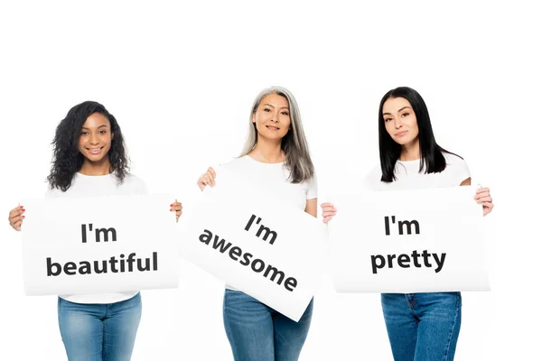 Happy multicultural women holding posters with lettering isolated on white — Stock Photo