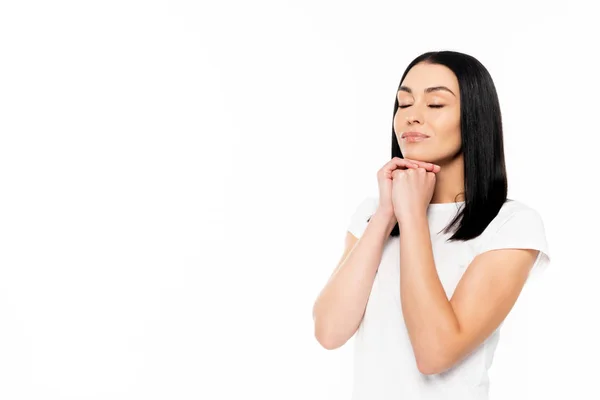 Atractiva mujer con los ojos cerrados y las manos apretadas aisladas en blanco - foto de stock