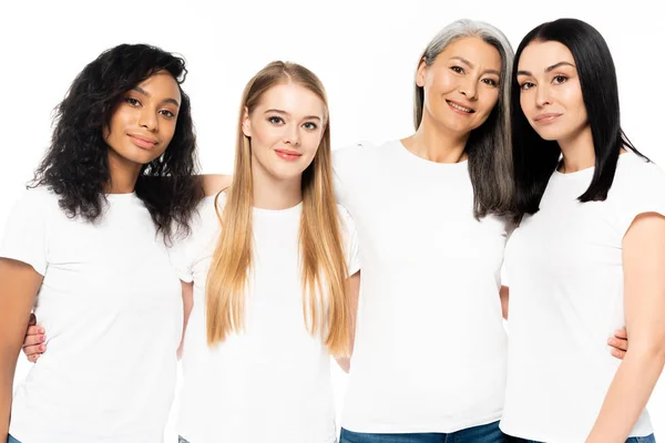 Happy multicultural women in white t-shirts looking at camera isolated on white — Stock Photo