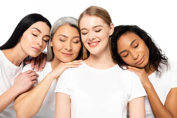 Mulheres multiculturais alegres em camisetas brancas com olhos fechados isolados em branco — Fotografia de Stock
