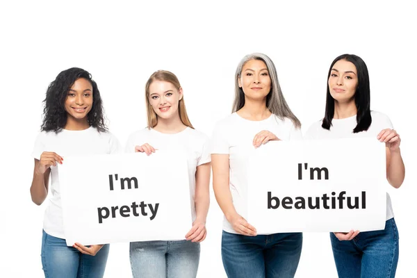 Heureuses femmes multiculturelles en jeans denim tenant des pancartes avec lettrage isolé sur blanc — Photo de stock
