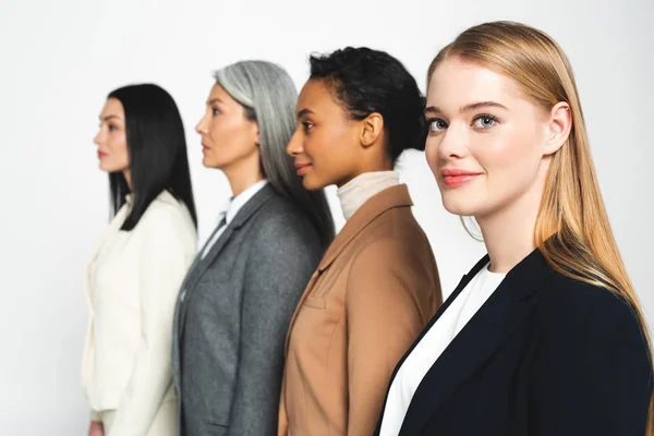 Foco seletivo de quatro mulheres de negócios atraentes e multiculturais isoladas em branco — Fotografia de Stock