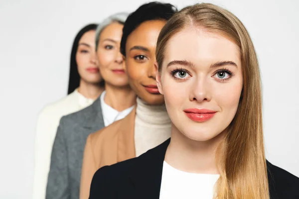 Enfoque selectivo de cuatro empresarias atractivas y multiculturales mirando a la cámara aislada en blanco - foto de stock