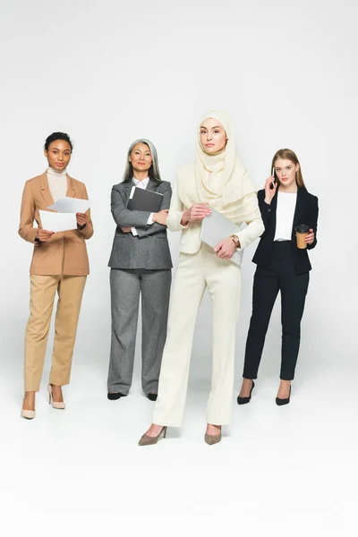 Attractive multicultural businesswomen near arabian woman with laptop on white — Stock Photo