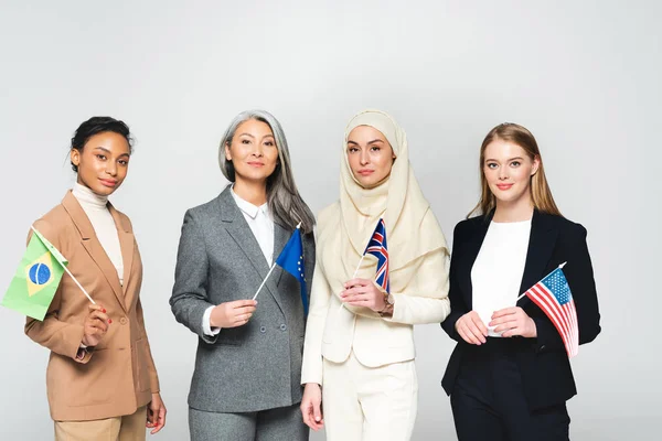 Mujeres multiculturales con banderas de diferentes países aisladas en blanco - foto de stock