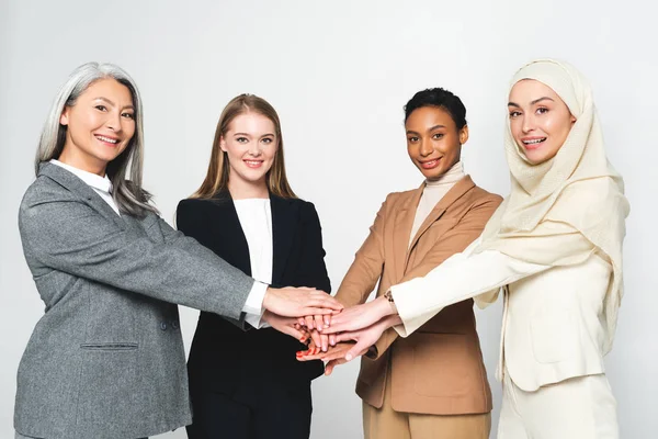Empresarias multiculturales poniendo las manos juntas aisladas en blanco - foto de stock