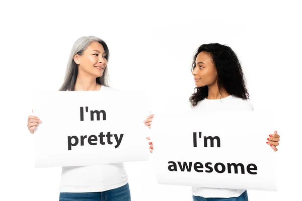 Feliz afro-americano e asiático mulheres segurando cartazes com letras isoladas no branco — Fotografia de Stock