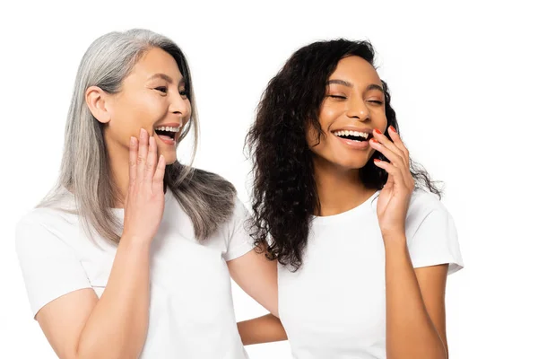 Fröhliche afrikanisch-amerikanische und asiatische Frauen lachen isoliert auf weiß — Stockfoto